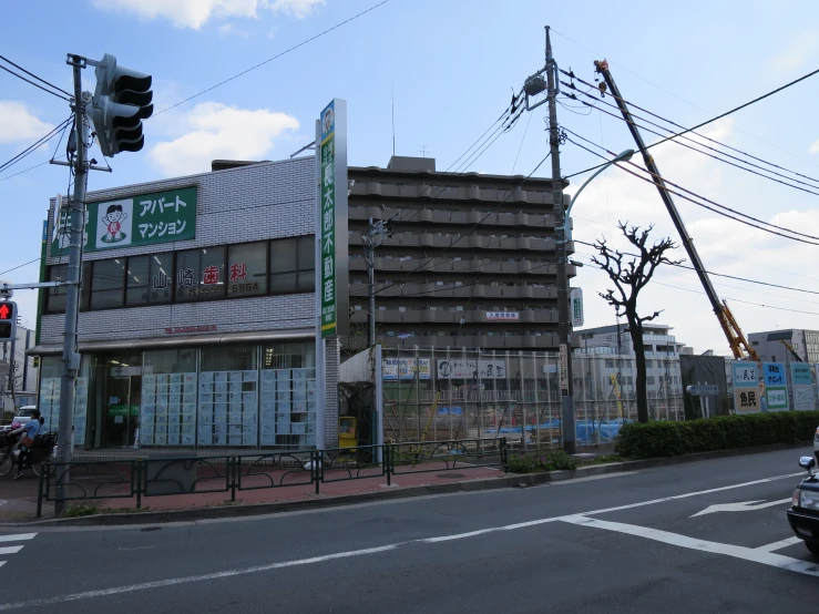 a street intersection with cars driving past an old japanese shopping center