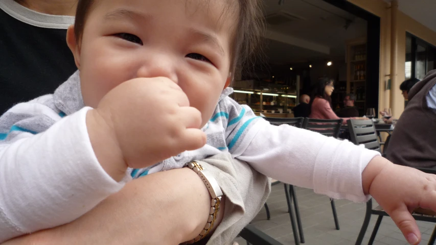 a small child holding onto someones hand with a bite in its mouth