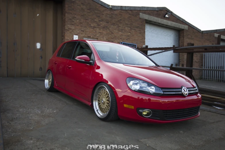 red vw golf with gold wheels in an outside garage