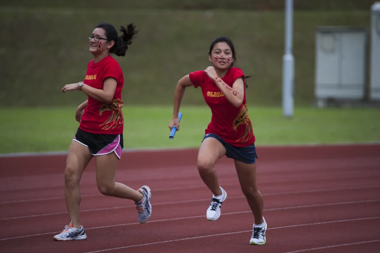 two women running on a track wearing running clothes