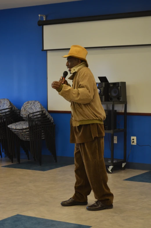 a man standing in a room wearing a yellow hat