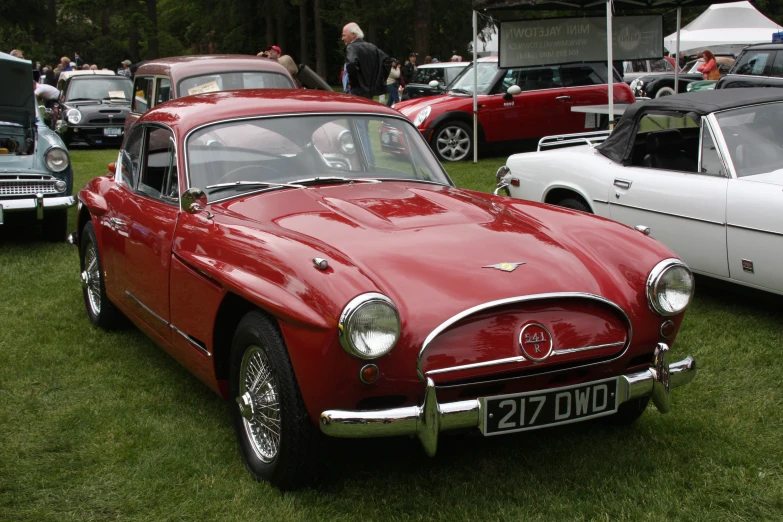 an old red car parked at a car show