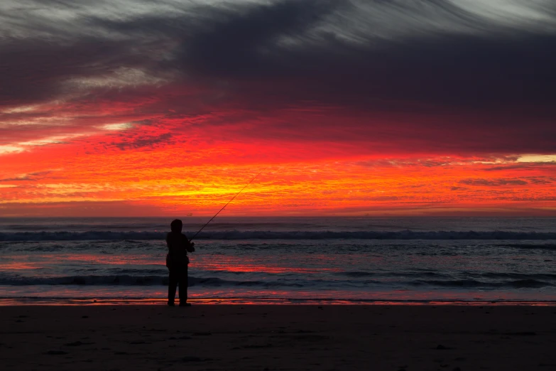 silhouette of a man with fishing rods against the sunset