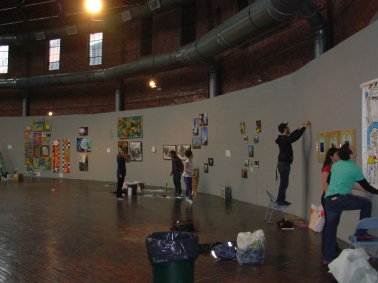 a group of people are doing art work inside of an empty space