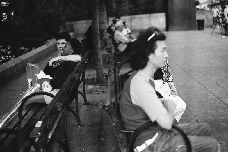 black and white image of a person sitting on a bench and another sitting down