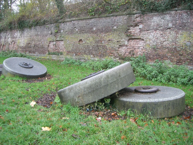 a park bench sitting in the grass with a brick wall behind it