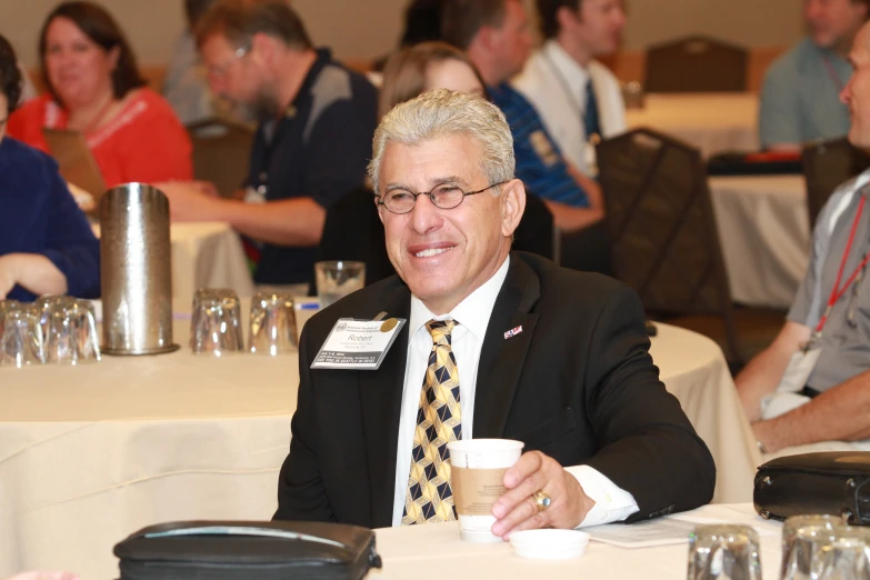 an older man in glasses and a neck tie sitting at a table