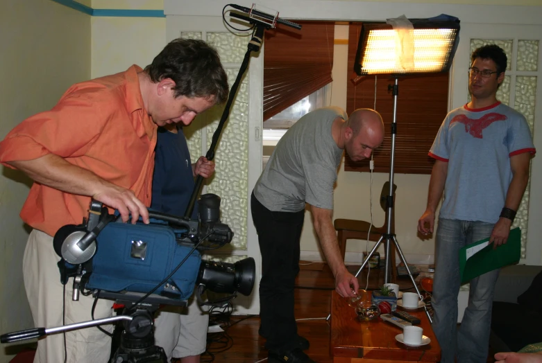 men with cameras are gathered around in a living room