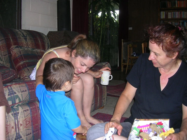 a woman and two children are on the couch playing with toys