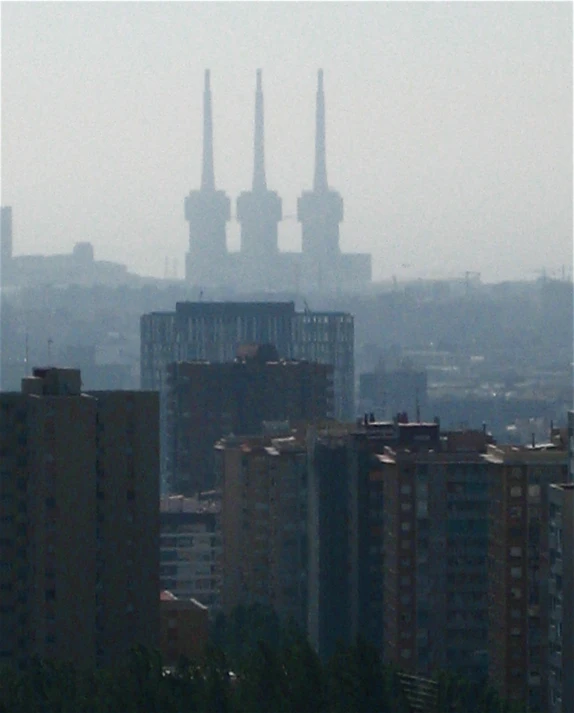 a large area of tall buildings with smoke stacks behind them