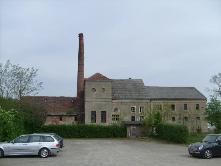 a large building with many windows sitting next to two small cars