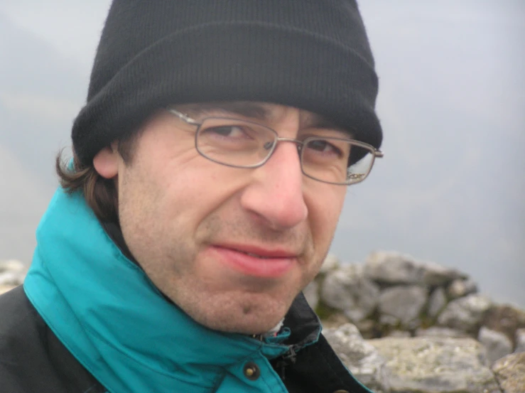 a man wearing glasses, a blue scarf and a beanie