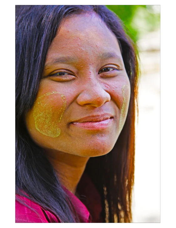 a woman is smiling and wearing a yellow sticker on her face