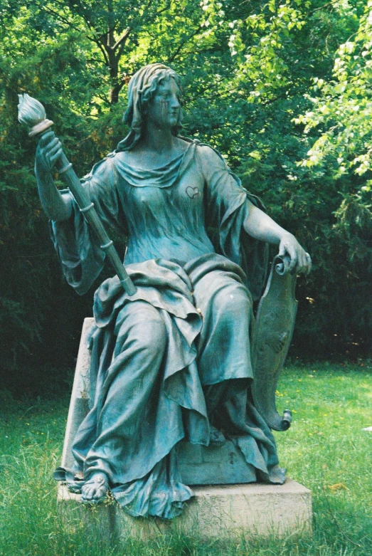 the statue is sitting in the park with a cellphone