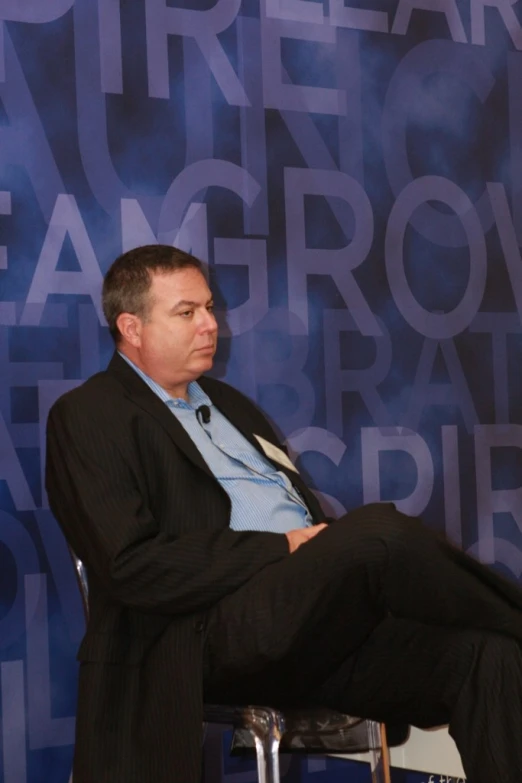 a man sitting in a chair talking on a stage