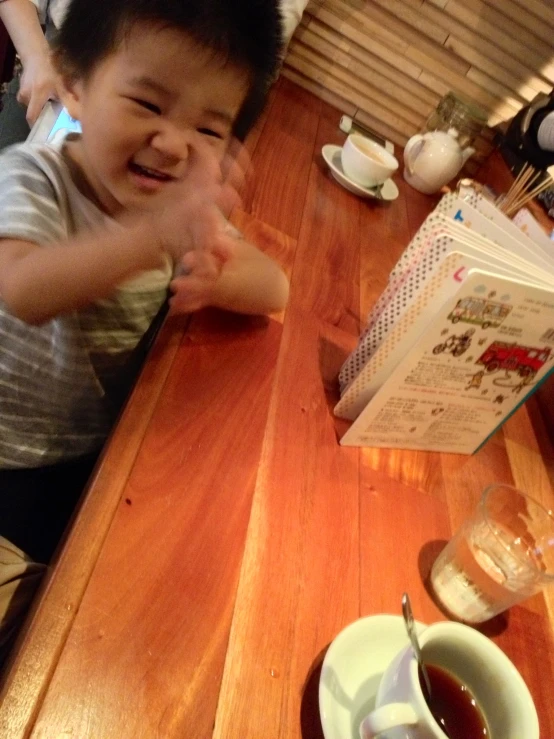 a  smiling with his hands up in front of a cup and saucer