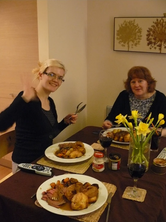 two women sitting at a table with plates of food