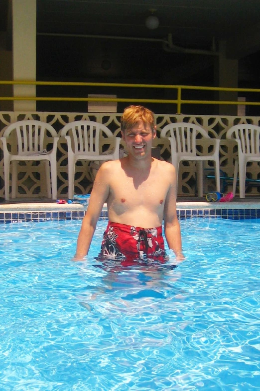 a man wearing red trunks while standing in a swimming pool