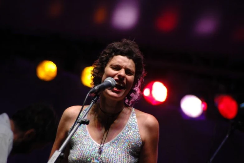 a woman singing into a microphone with a disco light in the background