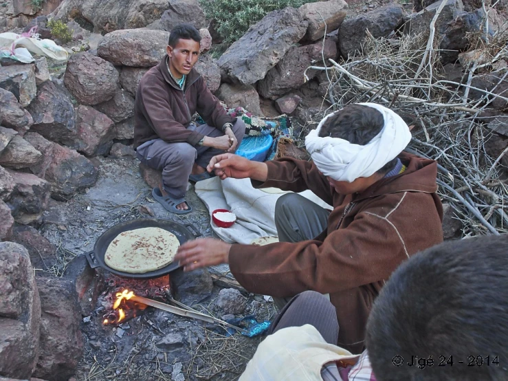 men sit around a campfire and cook on the ground