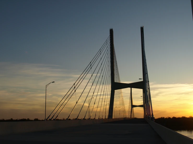 a bridge over water with the sun setting