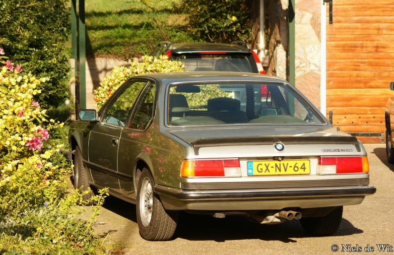 an old bmw is parked next to a house