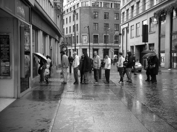 a city sidewalk in the rain with people walking