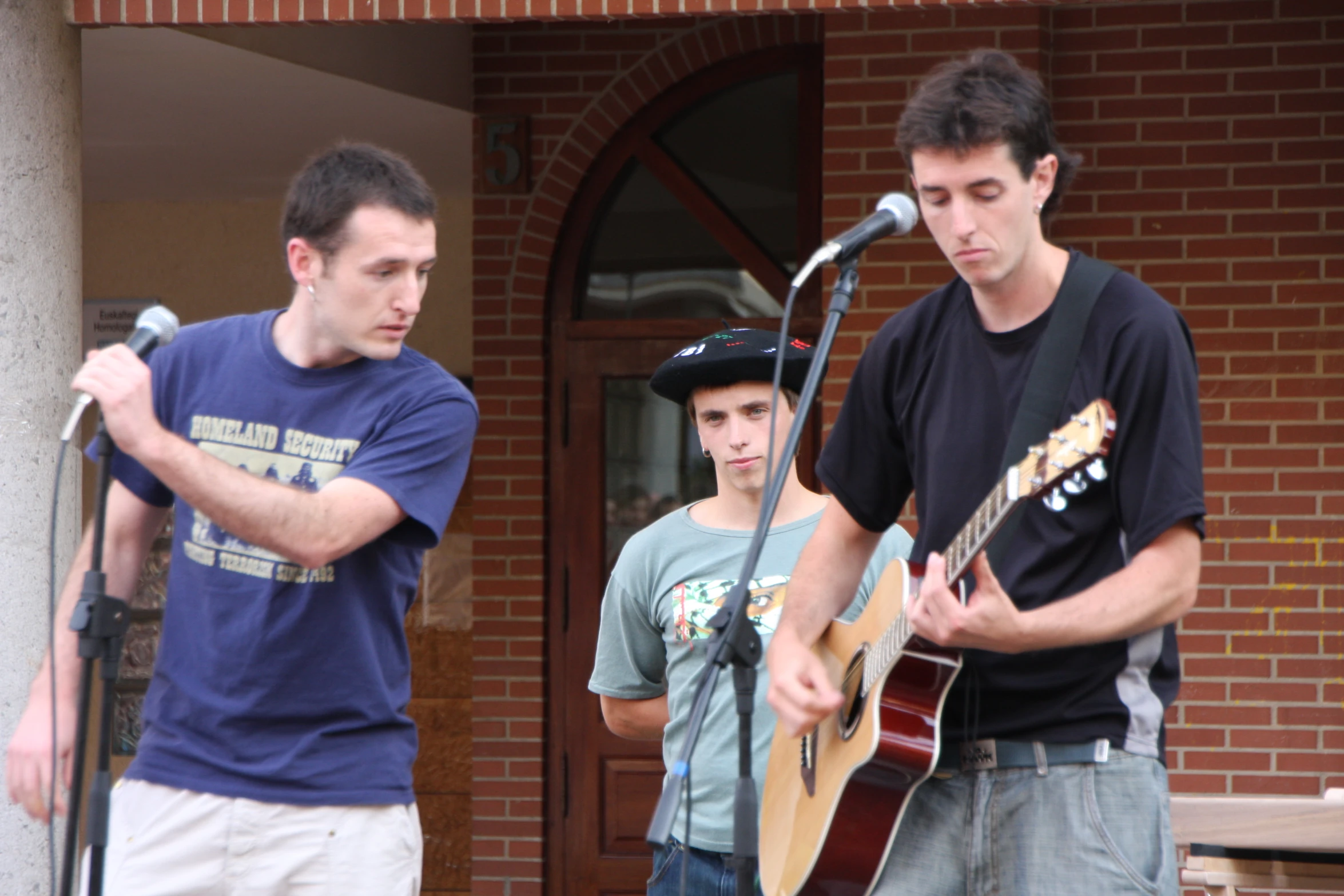 two men in front of a microphone, one playing an acoustic guitar