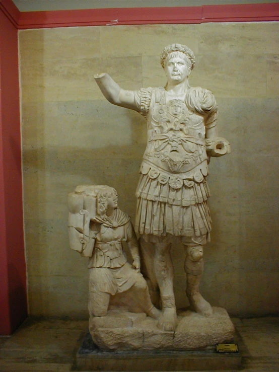 an ancient statue with a man standing beside it