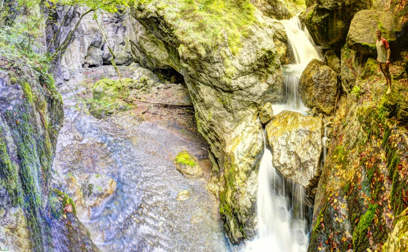 people are standing in the water at a rocky area with waterfalls