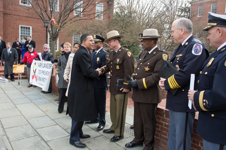 several uniformed men stand in a group by some trees