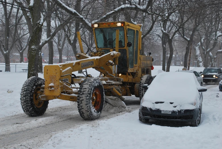 a snow plow and a vehicle parked on a snowy road