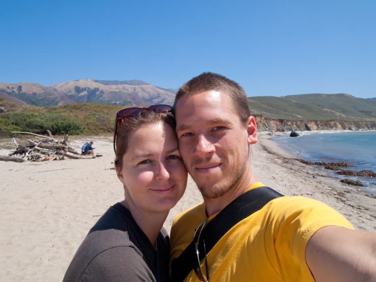 a couple taking a selfie on the beach by the water