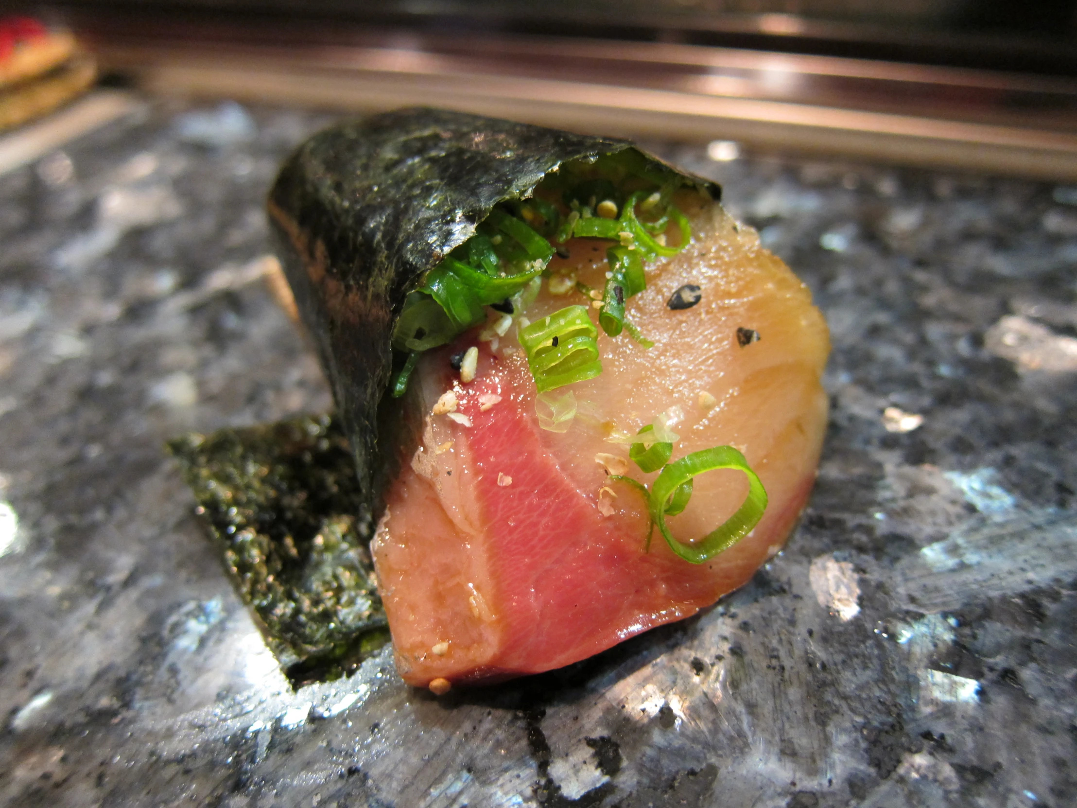 an image of a sushi with chop sticks and scallions on it