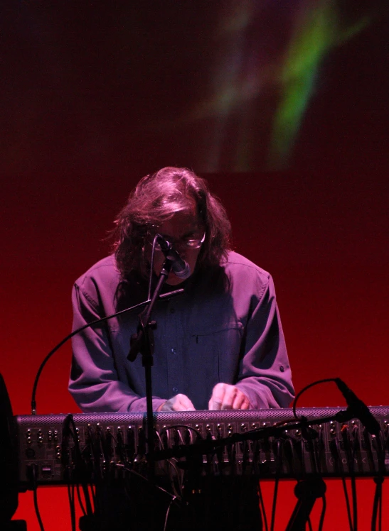 a man in a blue shirt is playing a keyboard