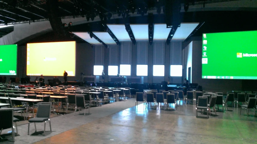 a large empty, clean dining hall with large tv screens on the wall