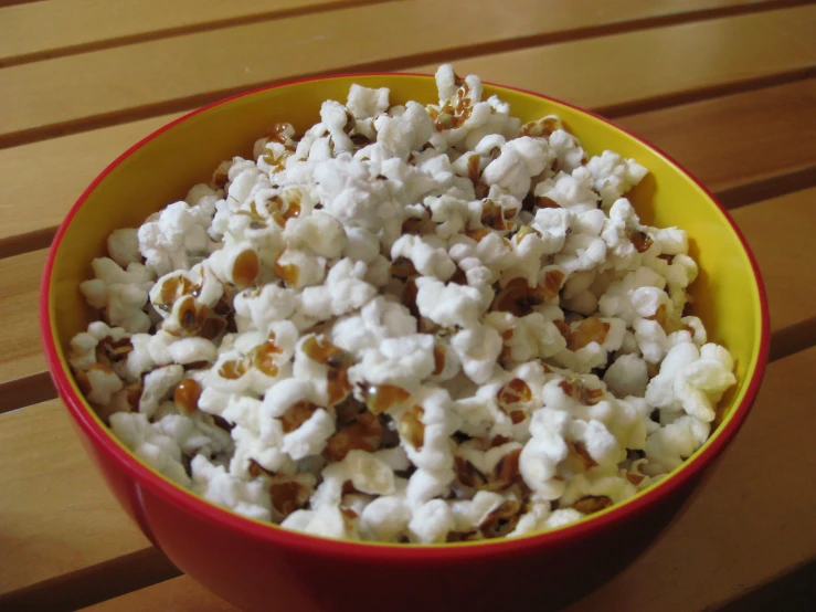 a bowl full of popcorn sitting on top of a wooden table