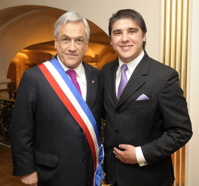 two men wearing suits are posing for the camera