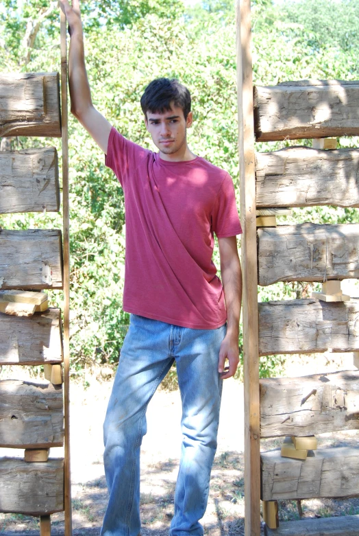 a man standing outside leaning against a wooden structure