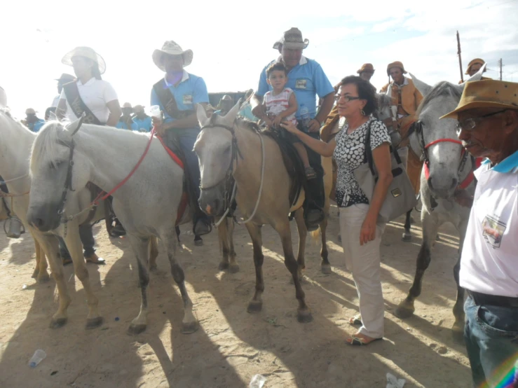 a group of people are gathered around horses