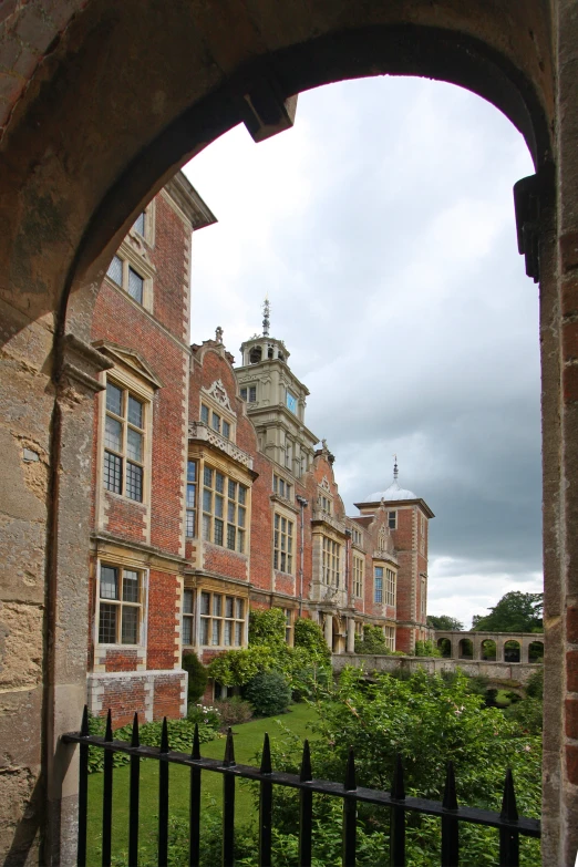 a view from behind an open gate into a courtyard with a black gate in front of buildings