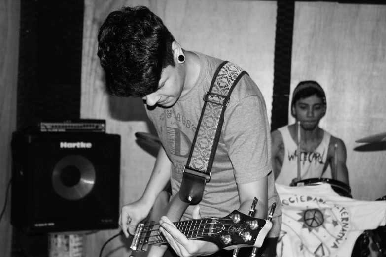 a young man playing an electric guitar with another playing a band