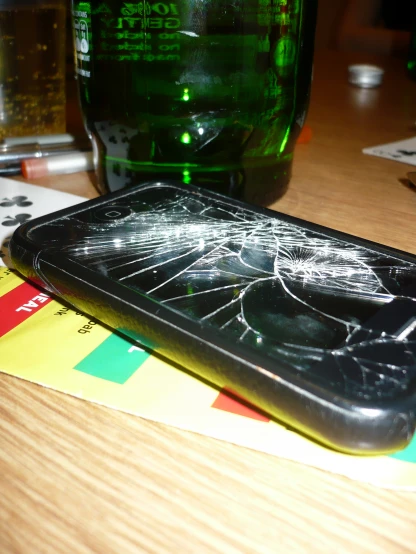 a shattered iphone sitting on top of a wooden table