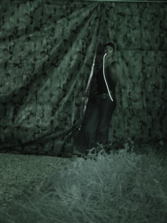 the dark image shows a man leaning up against a curtain