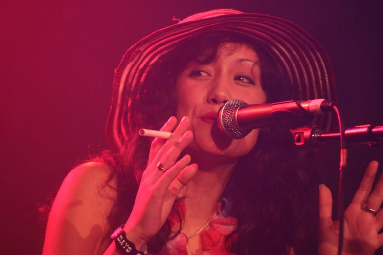 an asian woman in front of a microphone holding a cigarette