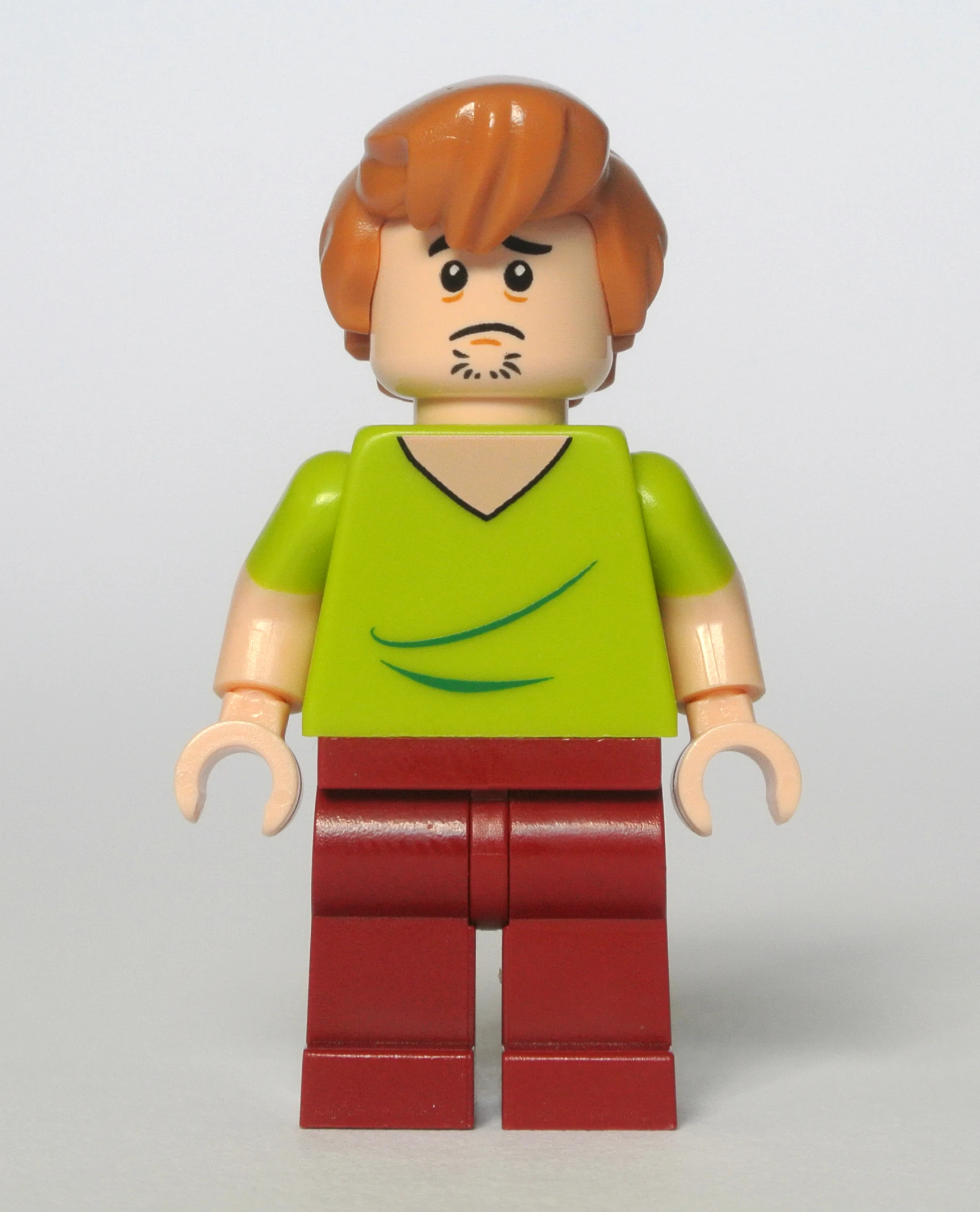the small lego person has red hair and green shirt