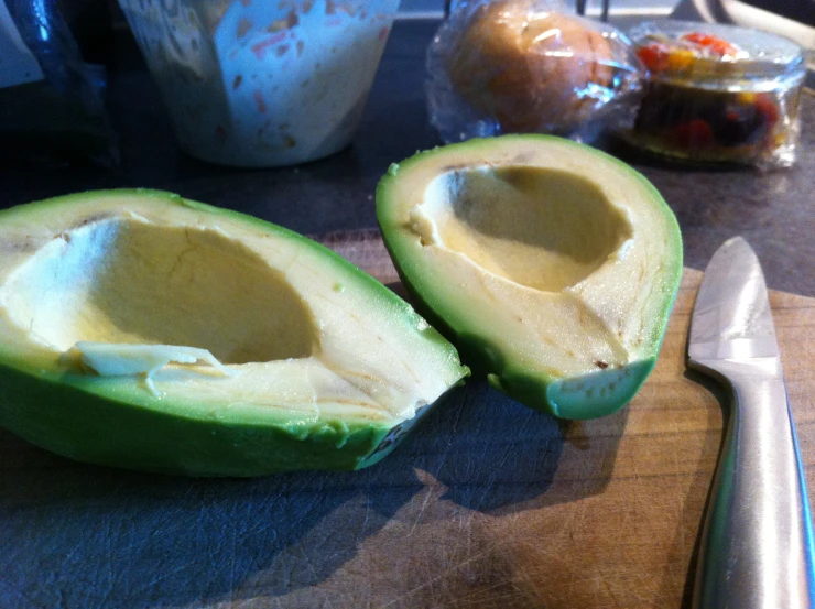 an avocado sliced in half on top of a  board