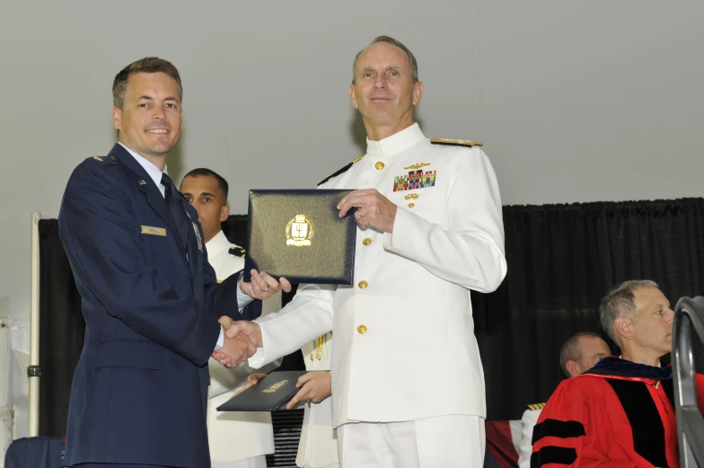 two men in uniform standing with one being the last person to receive an award