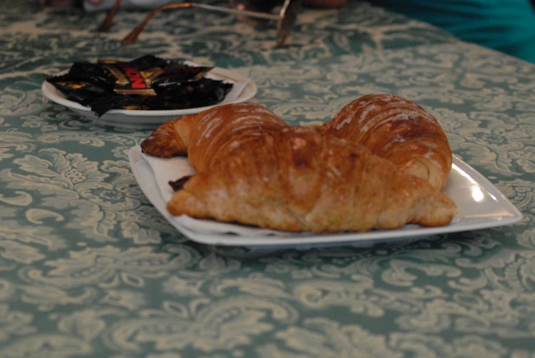 a plate filled with pastries next to an olive stuffed croissant