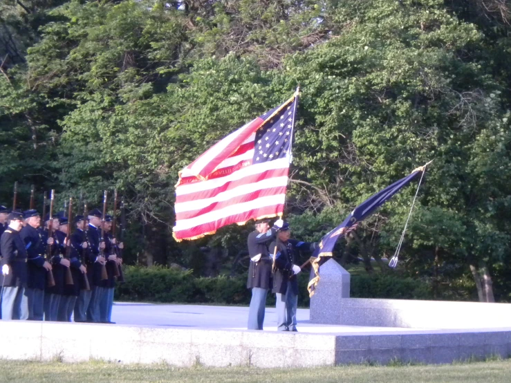 a group of men in military uniforms standing next to a flag